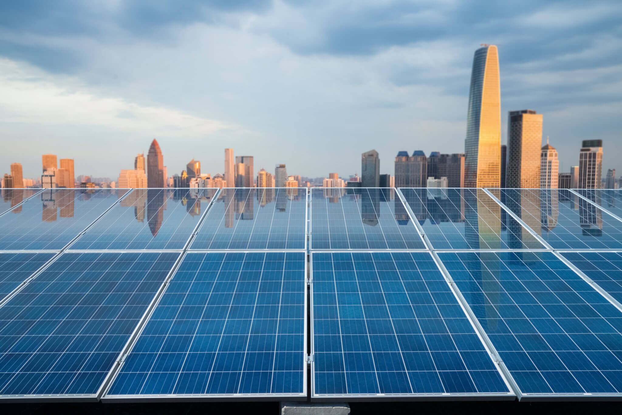 Solar panels with city skyline reflecting at twilight.