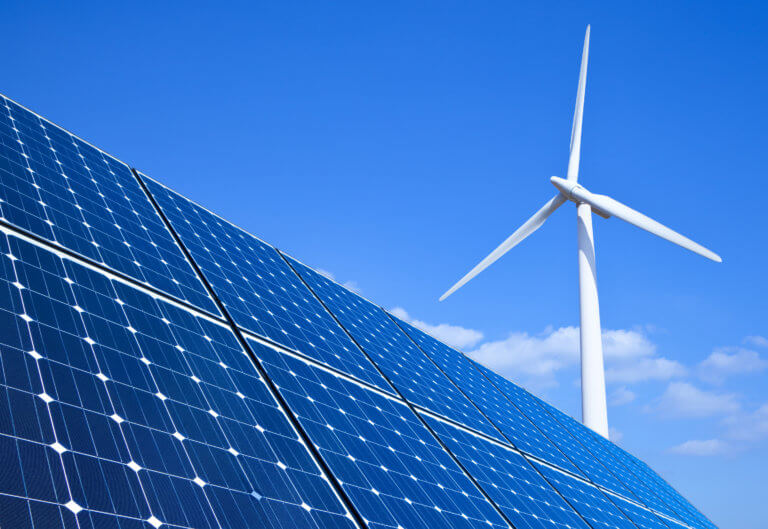 A blue sky with solar panels in the foreground and a wind turbine in the background, symbols of clean energy.