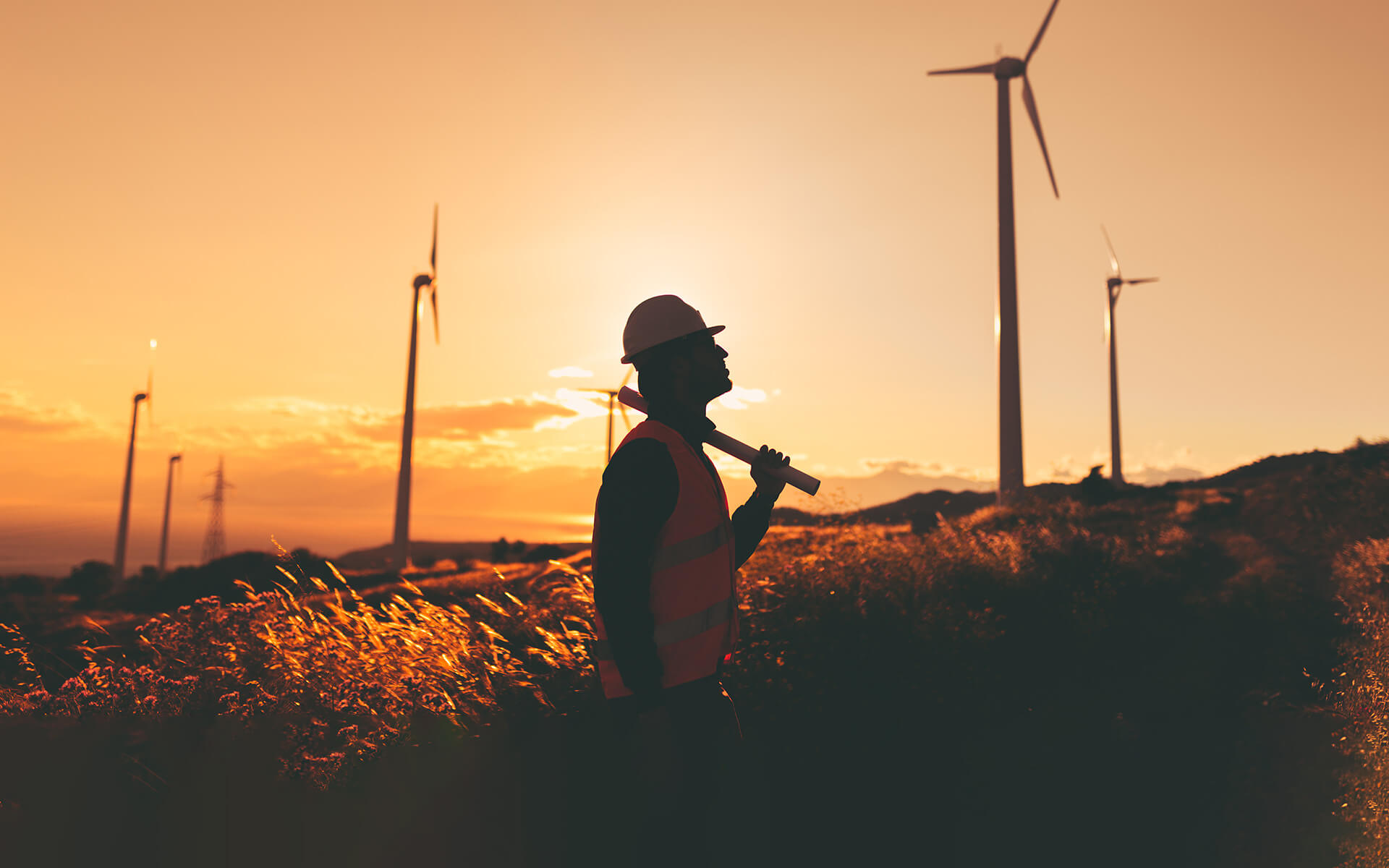 Silhouette of an engineer looking at wind turbines at dawn in Yonkers, NY.